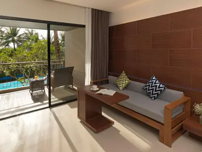 a living room with a couch and a balcony at Novotel Phuket Kata Avista Resort and Spa in Kata Beach