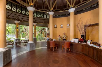 a lobby of a resort with two people at a bar at The Village Resort - SHA Plus in Karon Beach