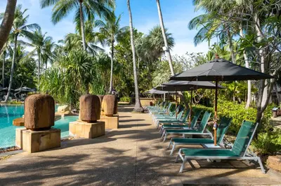 a row of lounge chairs with an umbrella next to a pool at Paradox Resort Phuket in Karon Beach