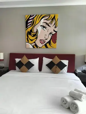a bedroom with a white bed with a painting on the wall at Kata Beach Studio Phuket in Kata Beach