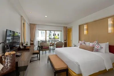 a bedroom with a large bed and a living room at Sawaddi Patong Resort & Spa by Tolani in Patong Beach