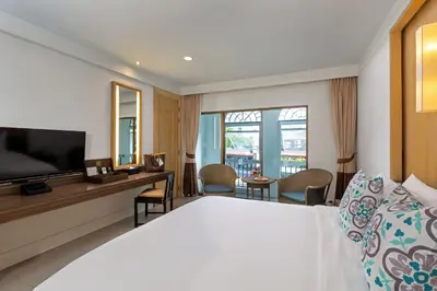 a hotel room with a bed and a desk and a television at Sawaddi Patong Resort & Spa by Tolani in Patong Beach