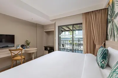 a bedroom with a large white bed and a desk at Sawaddi Patong Resort & Spa by Tolani in Patong Beach