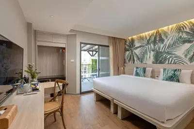 a bedroom with a large white bed and a desk at Sawaddi Patong Resort & Spa by Tolani in Patong Beach