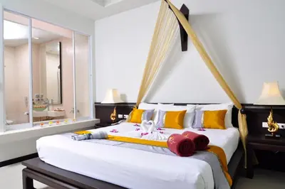 a bedroom with a large white bed with yellow and red pillows at Baan Karonburi Resort in Karon Beach
