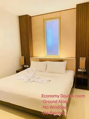 a bedroom with a large white bed with a window at The Album Hotel in Patong Beach