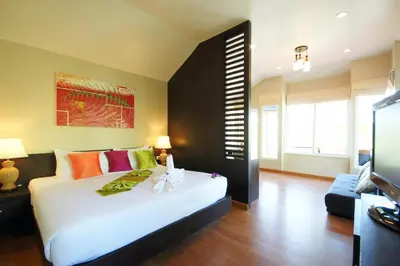 a bedroom with a large white bed with colorful pillows at Palm Paradise, Aonang Resort in Ao Nang Beach