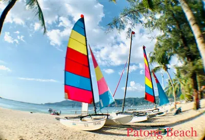 a row of sailboats sitting on the beach at Q Victory Patong Hotel in Patong Beach