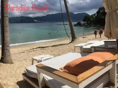 a beach with beds on the sand and the water at Q Victory Patong Hotel in Patong Beach