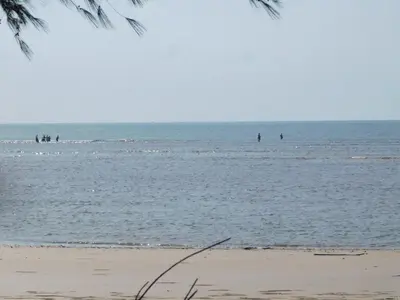 a group of people in the water at the beach at Phuket Sirinapha Resort in Nai Yang Beach