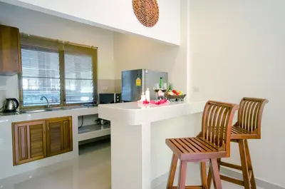 a kitchen with two chairs and a counter and a sink at Namphung Phuket Boutique Resort in Rawai Beach