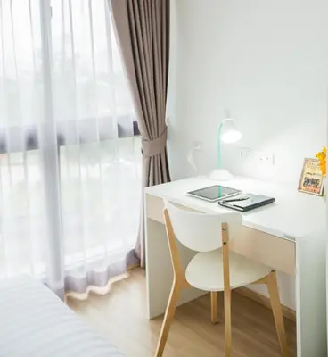 a white desk with a chair next to a window at Connext Residence Phuket in Phuket Town