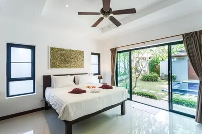 a bedroom with a bed and a ceiling fan at Frangipani pool villa - garden, BBQ & maid in Nai Harn Beach