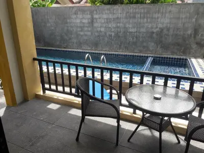 a patio with a table and chairs and a swimming pool at B Happy Resort - SHA ExtraPlus in Kamala Beach