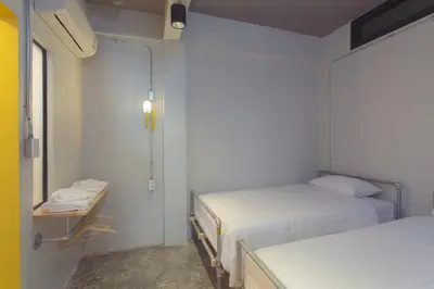 a small room with two beds and a window at Bloo Hostel in Phuket Town