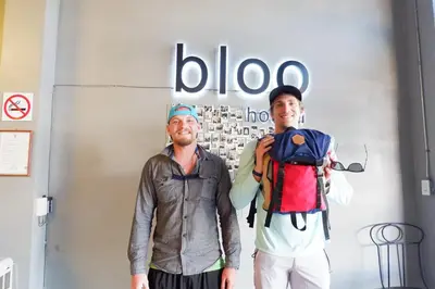 two men standing next to each other in front of a sign at Bloo Hostel in Phuket Town
