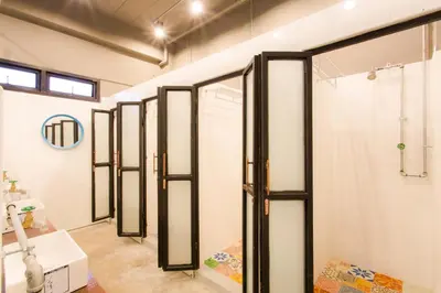a row of glass shower doors in a bathroom at Bloo Hostel in Phuket Town