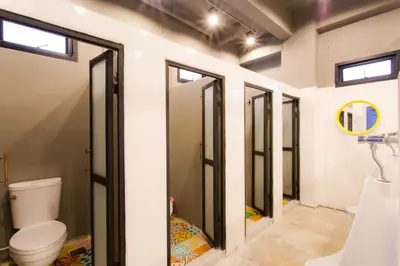 a bathroom with a toilet and some windows at Bloo Hostel in Phuket Town