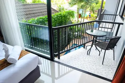 a room with a balcony with a table and a chair at The Umbrella House in Kamala Beach