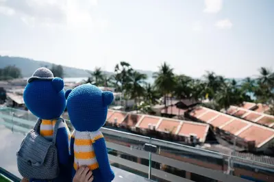 two people standing on a ledge looking at a city at BearPacker Patong Hostel in Patong Beach