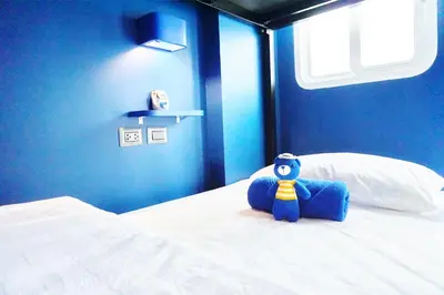 a blue bedroom with a teddy bear sitting on a bed at BearPacker Patong Hostel in Patong Beach
