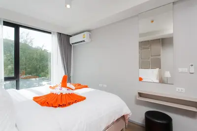 a bedroom with a bed with an orange dress on it at 6th Avenue Surin Beach - Official Account in Surin Beach
