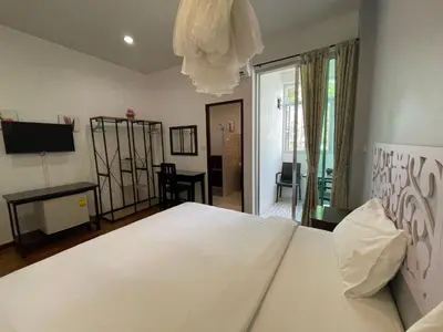 a bedroom with a large white bed and a television at Nawaporn Place in Phuket Town