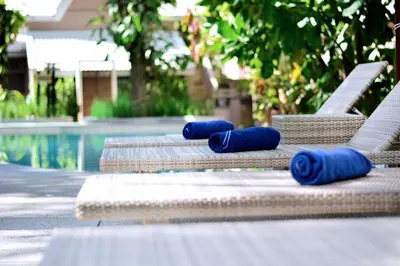 a row of chaise lounges with blue rolled up towels on them at Deevana Krabi Resort in Ao Nang Beach