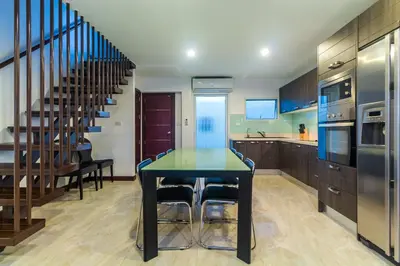 a kitchen with a dining table and a staircase at AP Grand Residence by Lofty in Kamala Beach