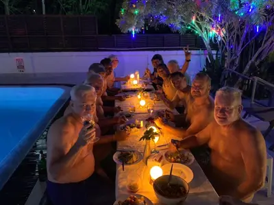 a group of men sitting at a long table by a pool at Phuket Gay Homestay in Kathu