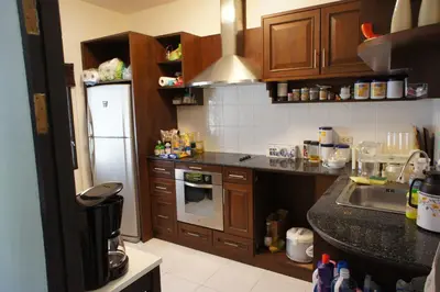 a kitchen with wooden cabinets and a sink and a refrigerator at Phuket Gay Homestay in Kathu