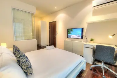 a bedroom with a bed and a desk and a tv at The Title Comfort Condotel in Rawai Beach
