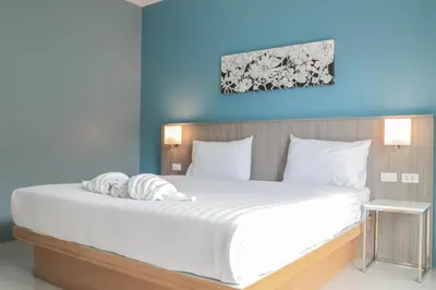 a bedroom with a large bed with white sheets at S2 Airport Residence in Nai Yang Beach