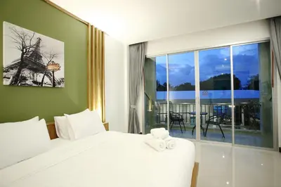 a bedroom with a white bed and a large window at The Malika Hotel - SHA Extra Plus in Phuket Town