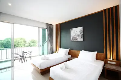two beds in a hotel room with a balcony at The Malika Hotel - SHA Extra Plus in Phuket Town