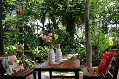 two white vases with flowers on a wooden table at Eat n Sleep in Phuket Town
