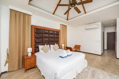 a bedroom with a large white bed with a ceiling fan at Villa Bond 3BR Private Pool Near Naiharn Beach in Rawai Beach