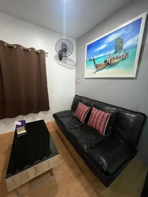 a black leather couch in a living room with a picture at 65 Pradit in Nai Yang Beach