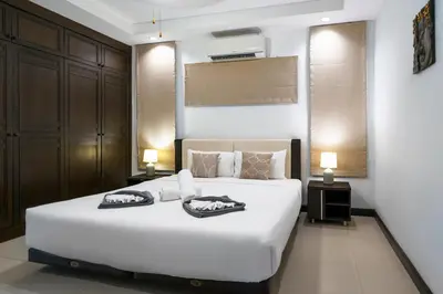a bedroom with a white bed with two shoes on it at Champagne Villa by G Estate in Rawai Beach