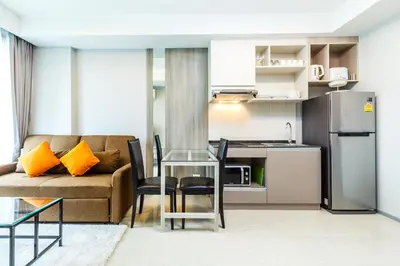 a living room with a couch and a kitchen at 6th Avenue Surin by Lofty in Surin Beach