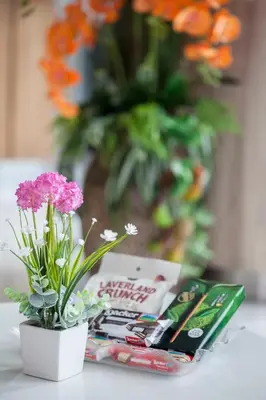 a vase with flowers on a table next to a magazine at The Elysium Residence - SHA Extra Plus in Chalong