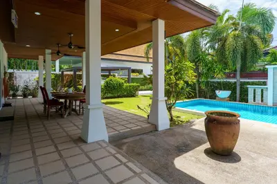 a covered patio with a table and a pool at Corton Villa by G Estate in Rawai Beach