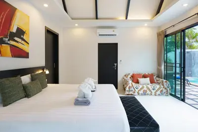 a bedroom with a large bed and a chair at Clos Vougeot Villa by G Estate in Rawai Beach
