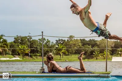 a man jumping into a swimming pool with a woman at Phuket Wake Park in Kathu