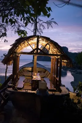 a boat with a straw roof on the water at Sunflower Boathouse in Phi Phi Don