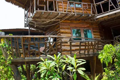 a wooden house with a deck in the woods at Sunflower Boathouse in Phi Phi Don