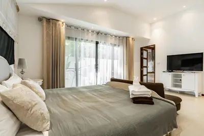 a bedroom with a large bed with a large window at Villa Andre by VillaCarte in Nai Harn Beach