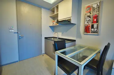 a small kitchen with a glass table and a blue door at 6th Avenue Surin by Risa in Surin Beach