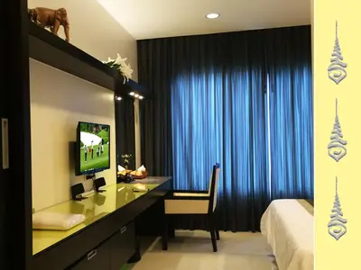 a bedroom with a desk and a bed and blue curtains at Apt S104 Kamala Regent in Kamala Beach