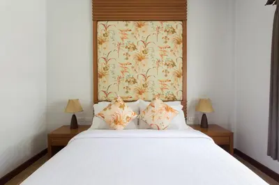 a bedroom with a white bed with a floral headboard at Alisea Pool Villa Aonang in Ao Nang Beach